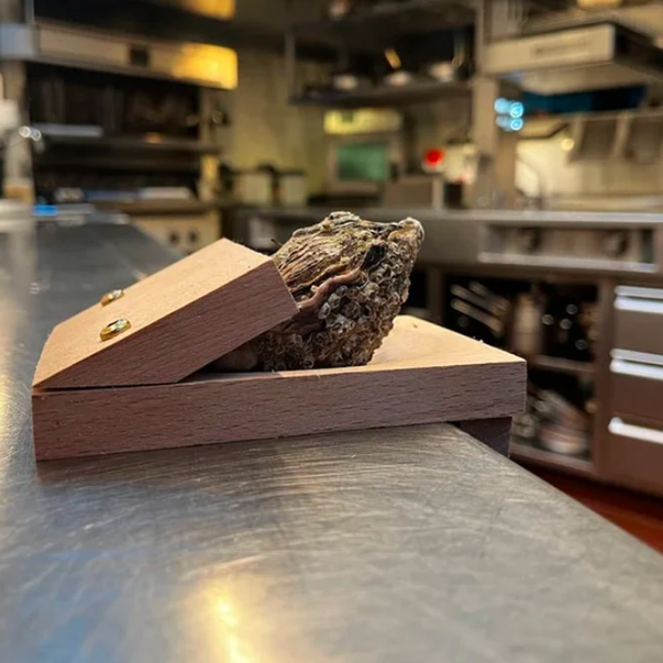 Safe oyster shucking tool: a sturdy wooden clamp that stabilizes oysters for easy and injury-free opening.