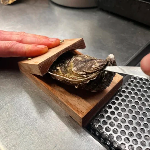 Robust wooden base oyster clamp, a secure seafood tool for safe and easy shucking in your kitchen.