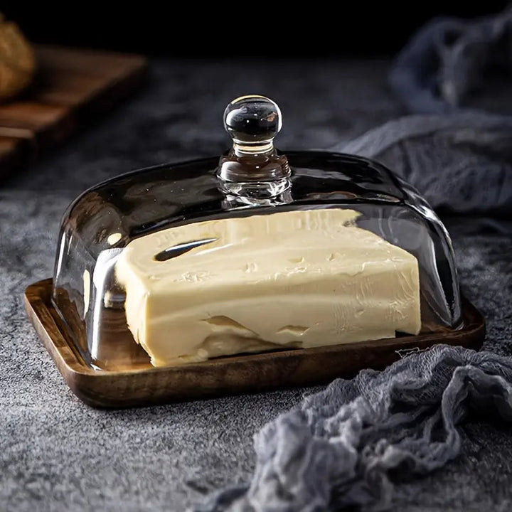 Farmhouse kitchen butter dish, featuring a stylish wood base & glass cover. Ideal dining decor accessory.