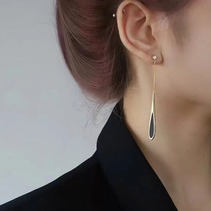 Woman wearing versatile black drop earrings, complementing a stylish outfit, a chic statement accessory.
