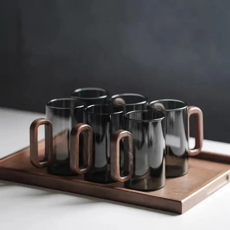 Durable borosilicate glass tumbler with ergonomic walnut handle, a sophisticated addition to any kitchenware collection.