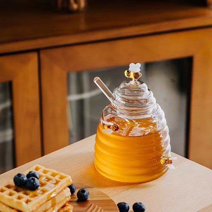 Clear glass honey dispenser in a beehive design, complete with a convenient honey dipper.