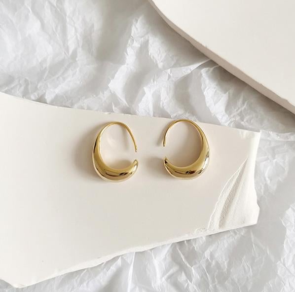 Woman wearing elegant gold dangle earrings, showcasing luxury jewelry and a timeless fashion accessory for women.