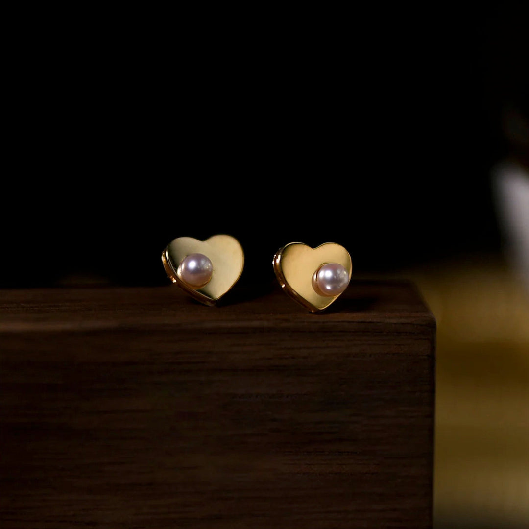 Delicate women's heart pearl stud earrings in gold, enhancing any elegant outfit
