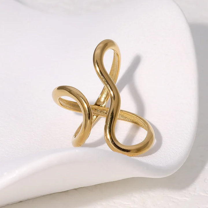 Close-up of a shimmering gold infinity wrap ring on a woman's hand, highlighting its water-resistant quality.