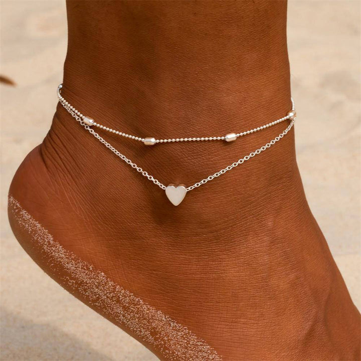 Elegant gold-plated double chain anklet with delicate heart charm for women. Adjustable fashion accessory.