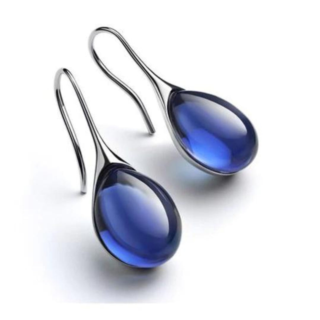 Close-up of elegant women's crystal drop earrings. Gold-plated dangle earrings, stylish fashion jewelry accessory.