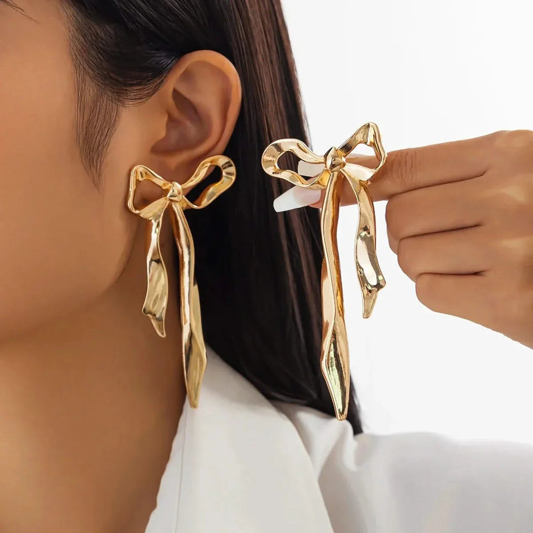 Elegant gold ribbon bow earrings for women. Dainty fashion jewelry, perfect gift for her, adds a chic touch.