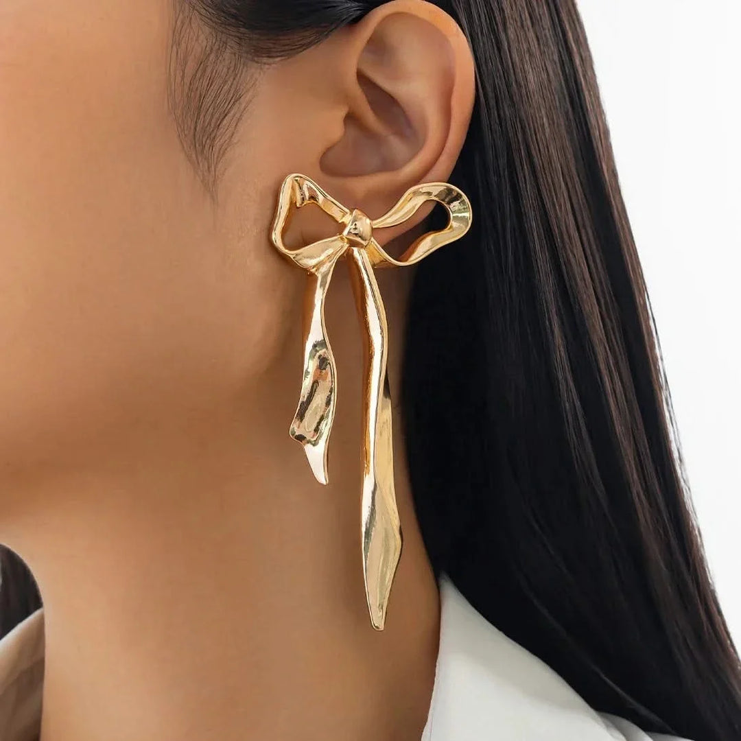Chic ribbon bow earrings, a delicate gold design. Elegant women's jewelry, perfect for any occasion.