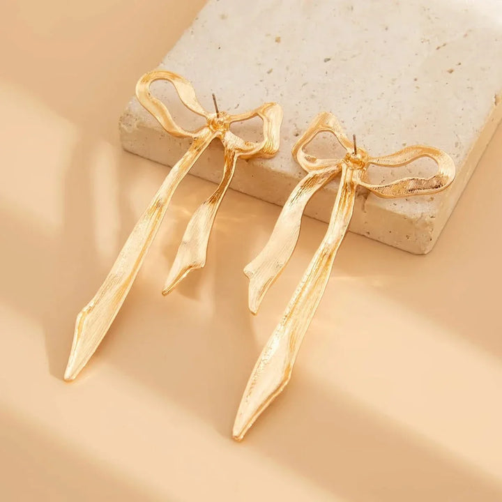 Fashionable bow earrings featuring an elegant ribbon. Dainty silver jewelry for women, ideal for gifting.