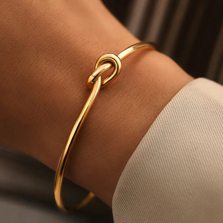 Elegant gold twisted knot bangle bracelet for women, a stylish adjustable jewelry accessory.