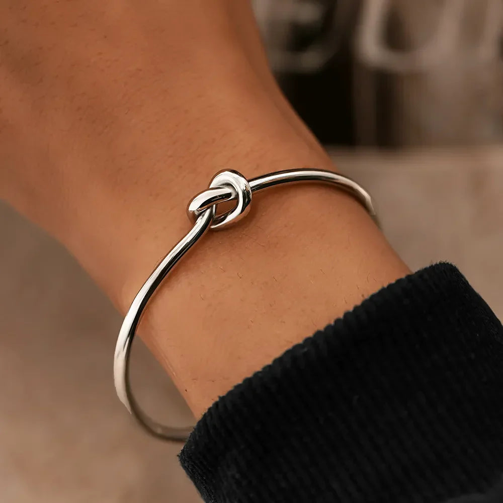 Close-up of a gleaming gold twisted knot cuff bracelet for women, perfect for gifting.