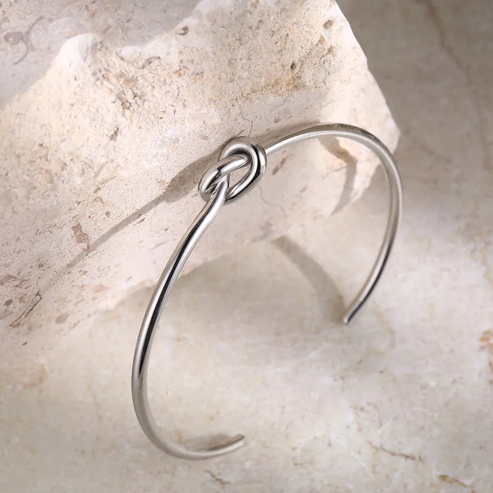 Detailed view of a fashionable women's gold twisted knot bangle, perfect for everyday wear.