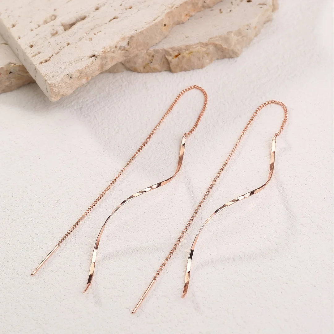 Close-up of elegant wave threader earrings, showcasing modern women's jewelry design.