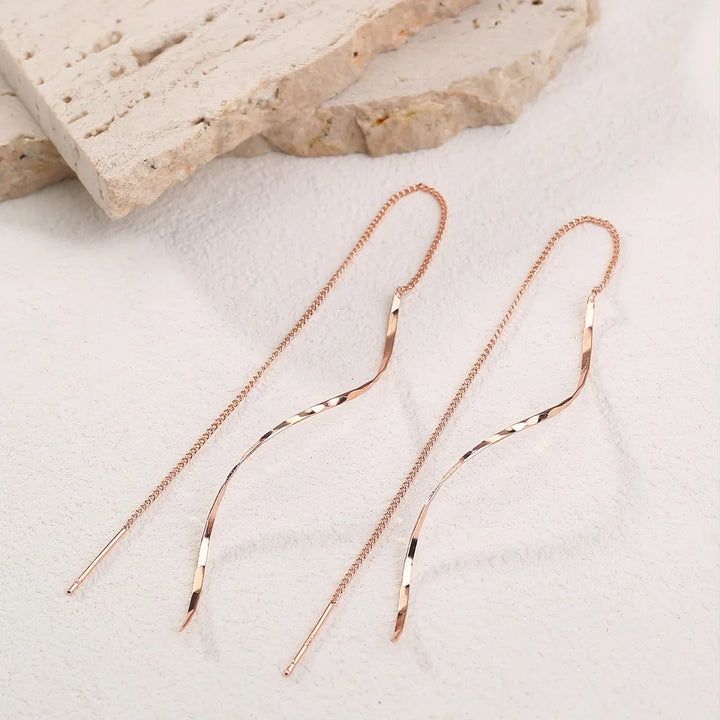 Close-up of elegant wave threader earrings, showcasing modern women's jewelry design.