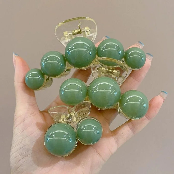Chic gold hair clip adorned with beautiful green pearls, perfect for an elegant hair accessory or updo.