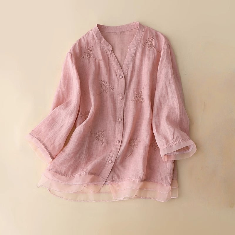 Elegant pink women's v-neck blouse with intricate embroidery and a contemporary layered hem, perfect for sophisticated style.