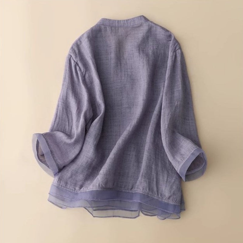 Close-up of elegant embroidered v-neck blouse for women, highlighting intricate patterns and a fashionable layered hem.