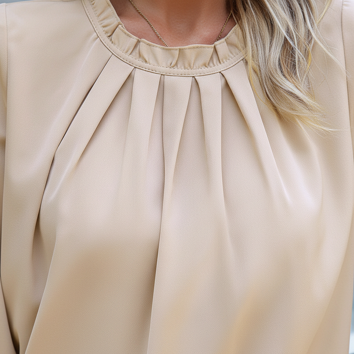 Close-up of the elegant pleated detailing on a women's long-sleeve blouse, autumn fashion.