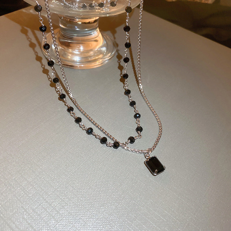 Close-up of an elegant women's silver double chain necklace, embellished with a sophisticated black pearl.