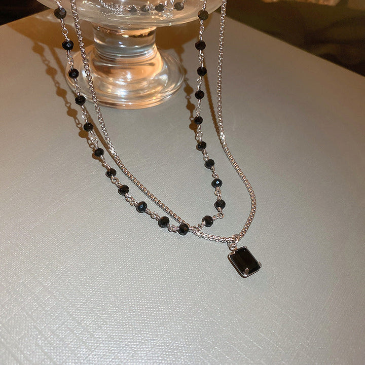 Close-up of an elegant women's silver double chain necklace, embellished with a sophisticated black pearl.