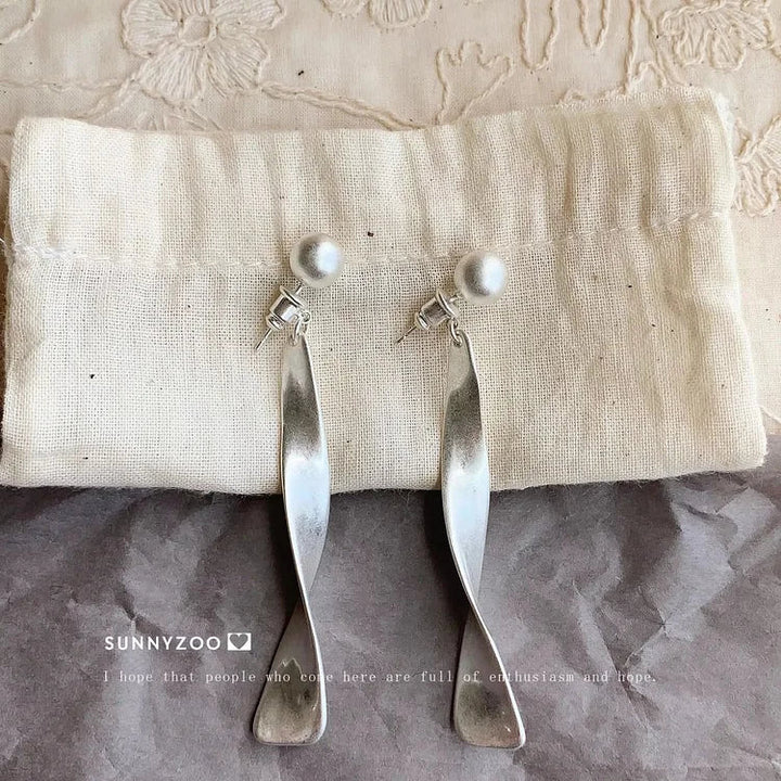 Close-up of women's delicate silver wave earrings. Unique, elegant design for fashion-forward women.