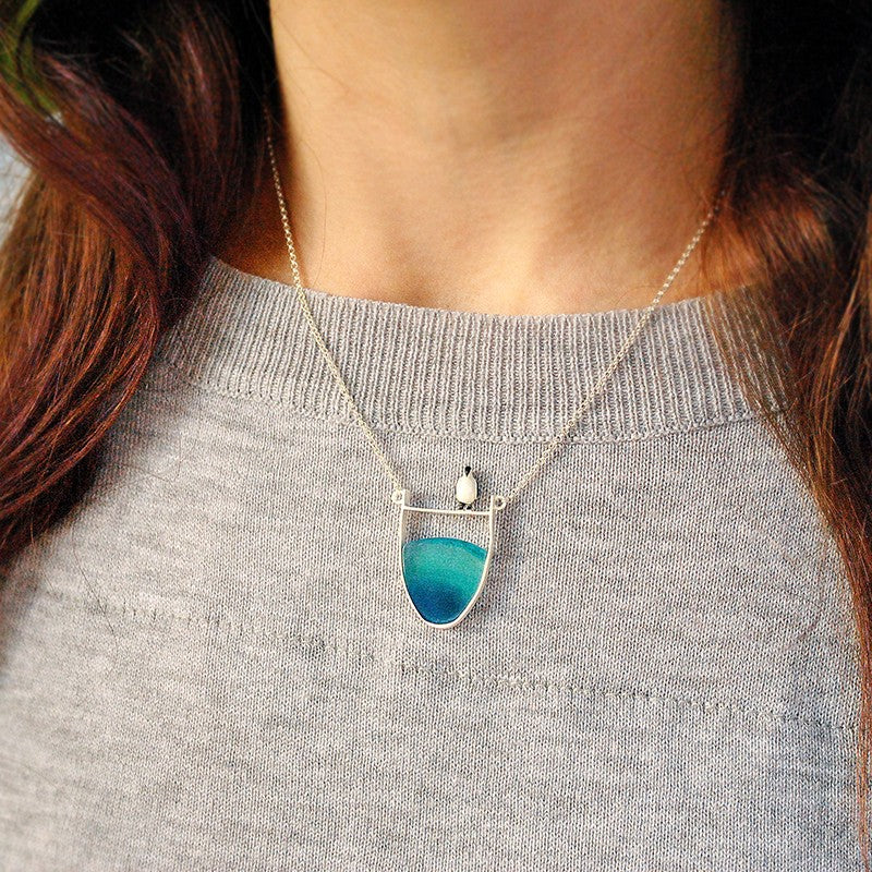 Close-up of a beautiful natural gray agate gemstone set in an elegant sterling silver pendant necklace.