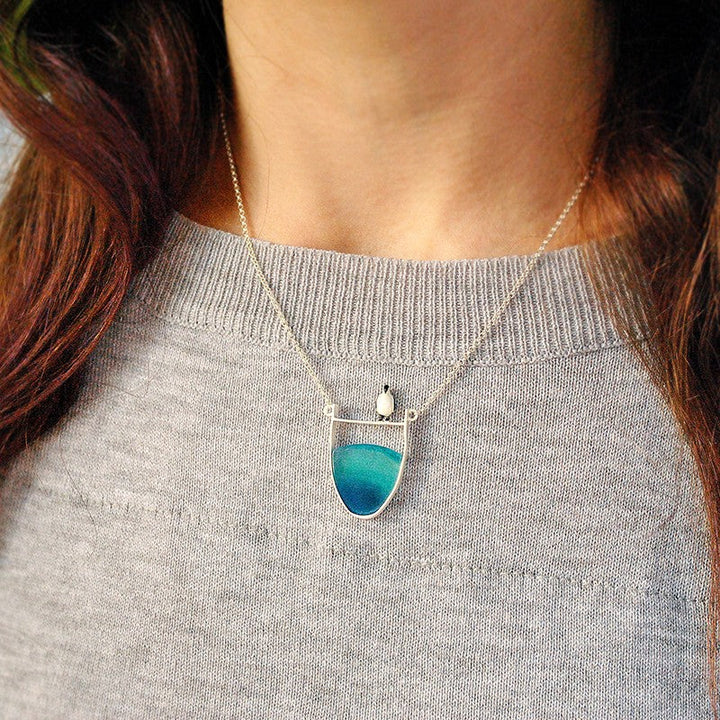 Close-up of a beautiful natural gray agate gemstone set in an elegant sterling silver pendant necklace.