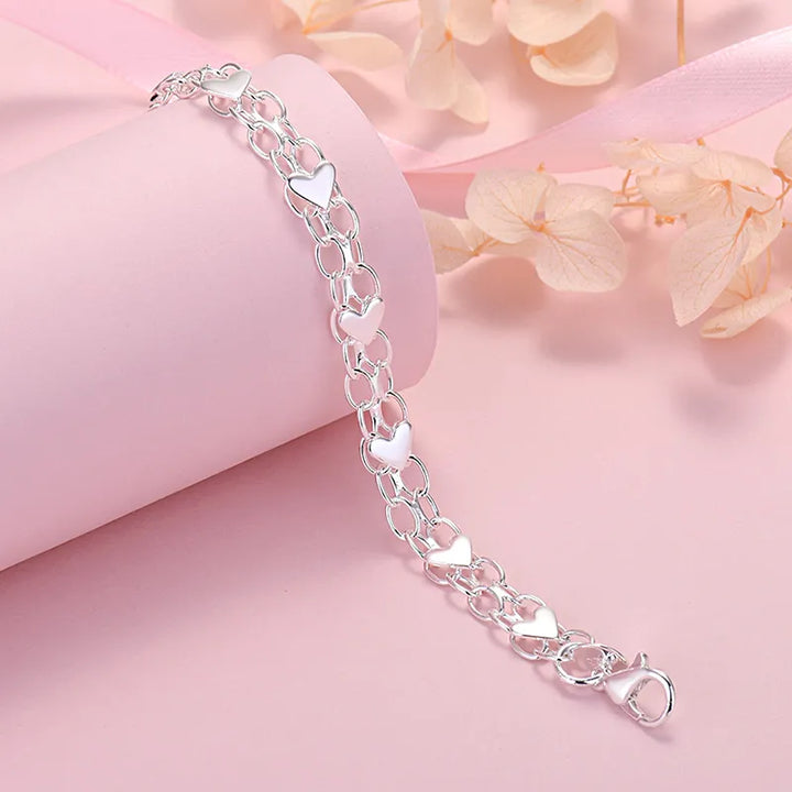 Close-up of a women's sterling silver heart bracelet, showcasing its classic elegance and adjustable design. Fine jewelry gift.