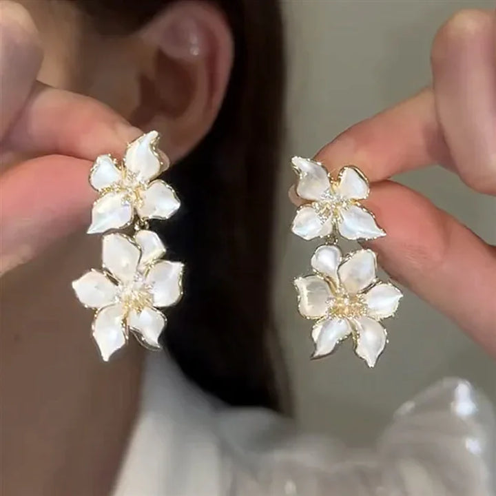 Close-up of delicate white floral drop earrings for women, elegant fashion accessory with intricate flower design & silver.