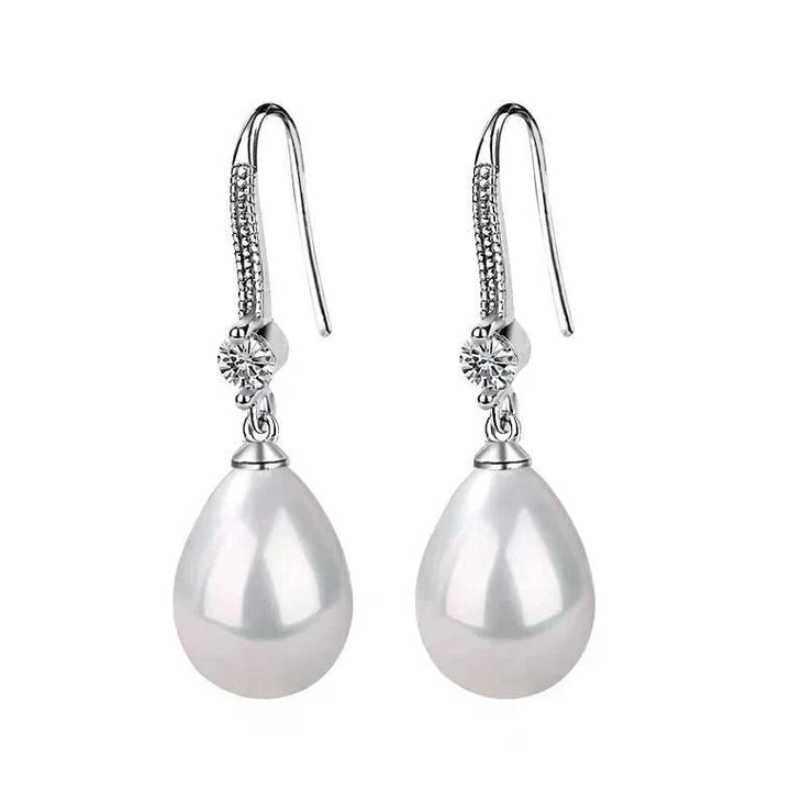 Elegant white oval pearl drop earrings for women, featuring lustrous pearls and sterling silver hooks. Timeless classic.