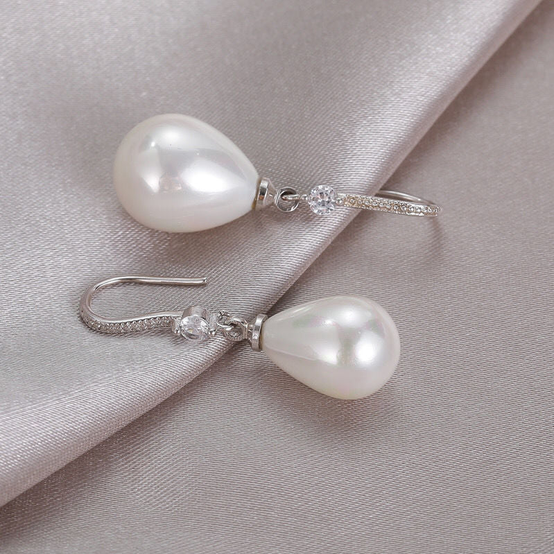 Timeless elegant white oval pearl drop earrings. Lustrous oval pearls on sterling silver hooks for women's jewelry.