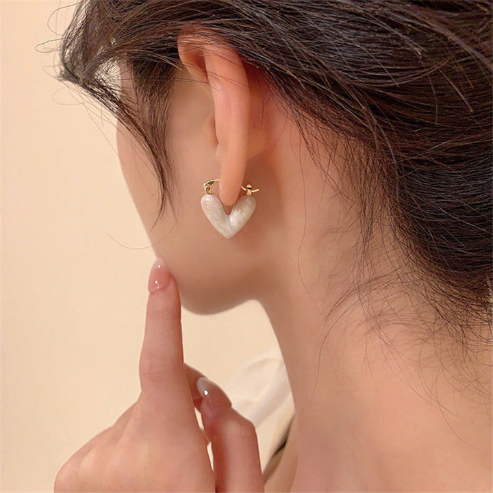 Detailed white teardrop dangle earrings, love-inspired. Elegant women's gold-plated jewelry accessory.