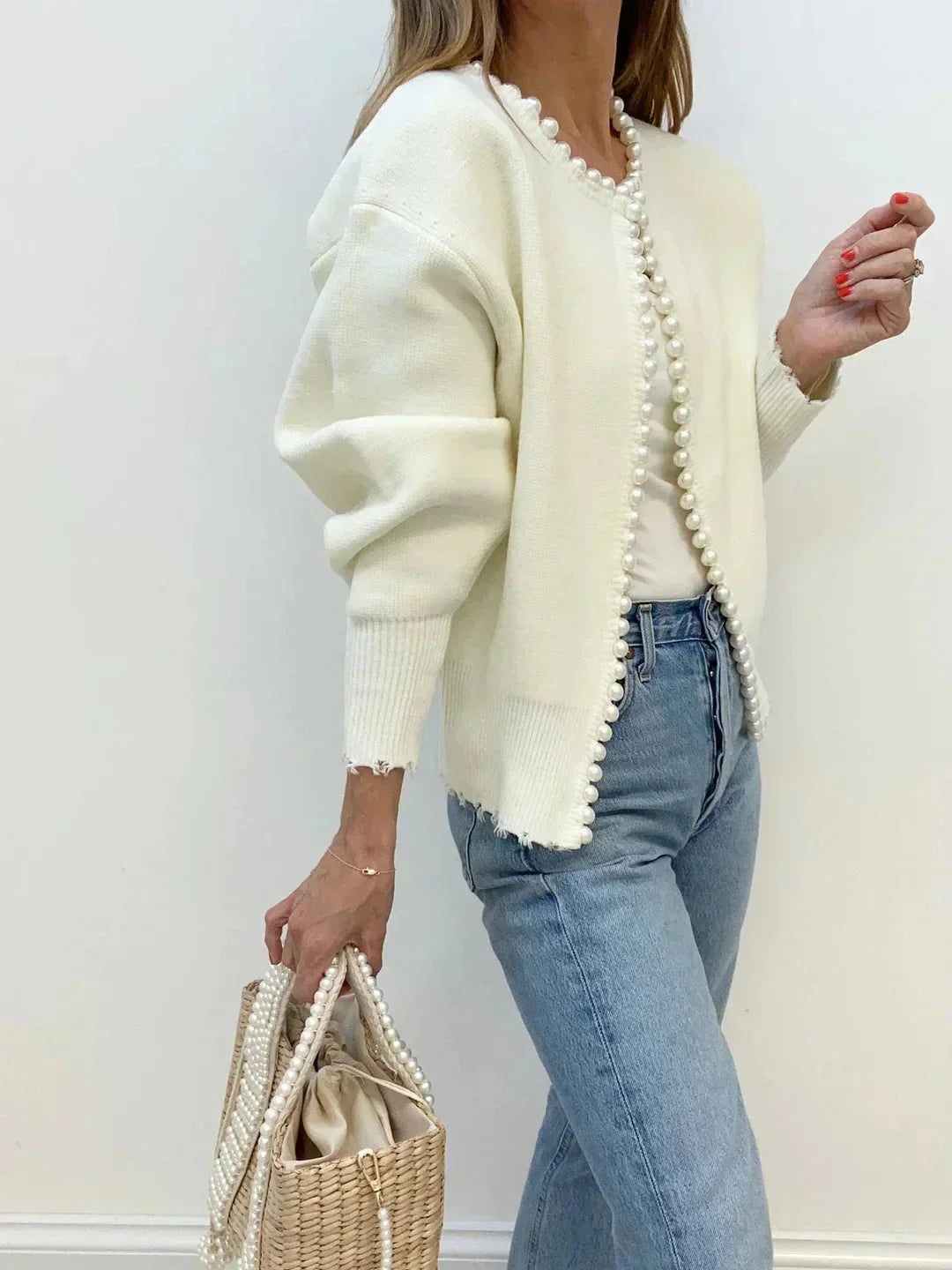 Close-up of pearl details on a soft knit women's cardigan. Round neck, long sleeve, timeless elegant fashion.