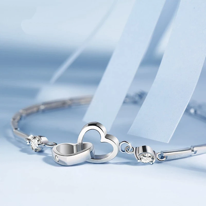 Close-up of a women's adjustable 925 sterling silver double heart bracelet with secure clasp. Fine jewelry.