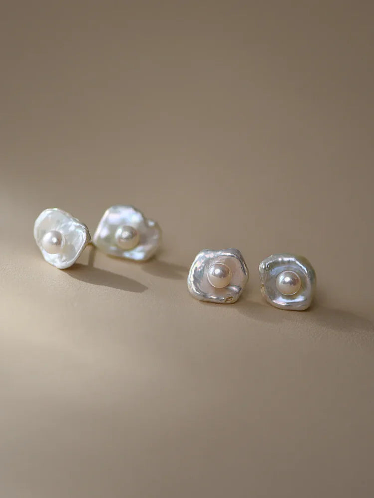 Close-up of women's sophisticated baroque pearl drop earrings, showcasing lustrous irregular pearls & silver setting.