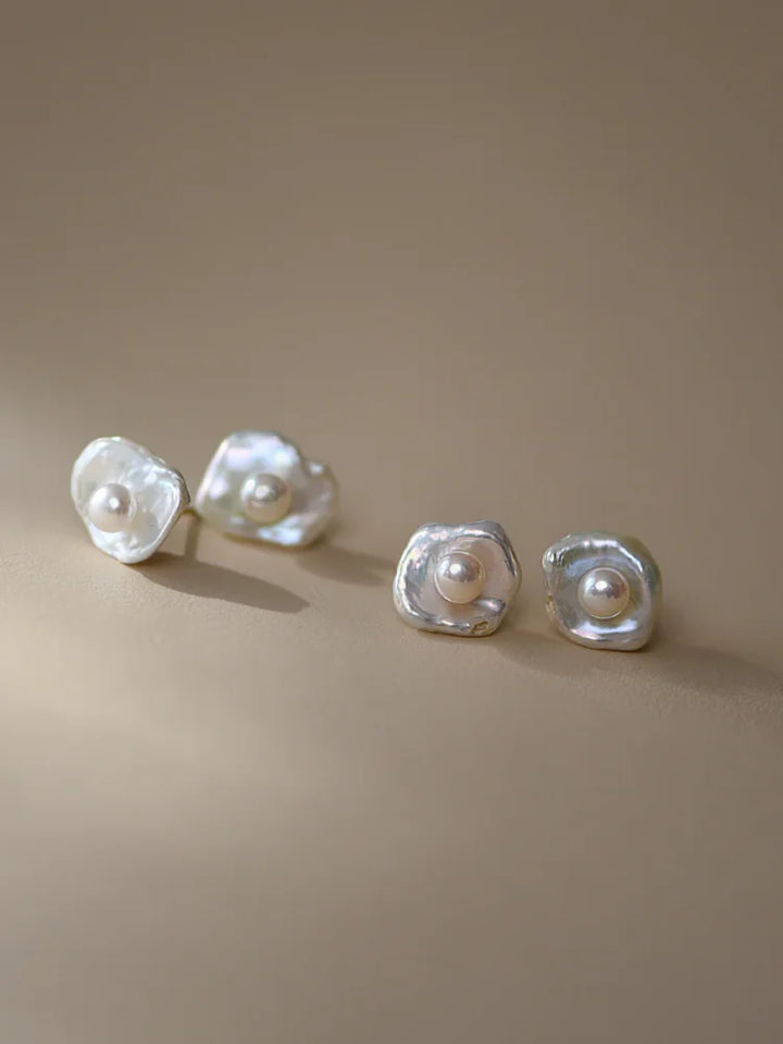 Close-up of women's sophisticated baroque pearl drop earrings, showcasing lustrous irregular pearls & silver setting.