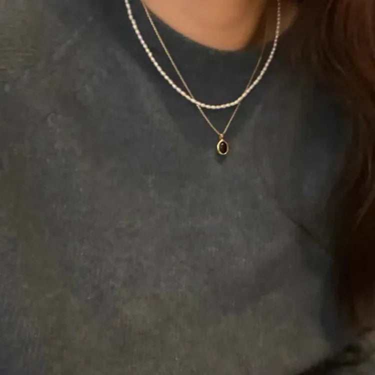 Woman wearing an elegant layered black onyx and pearl necklace set, perfect fashion accessory.