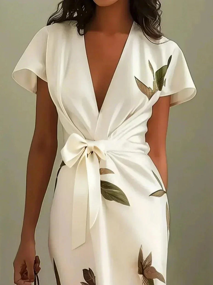 Women's midi dress with vibrant botanical floral print, V-neck, flutter sleeves, and an elegant bow-tie at the waist.