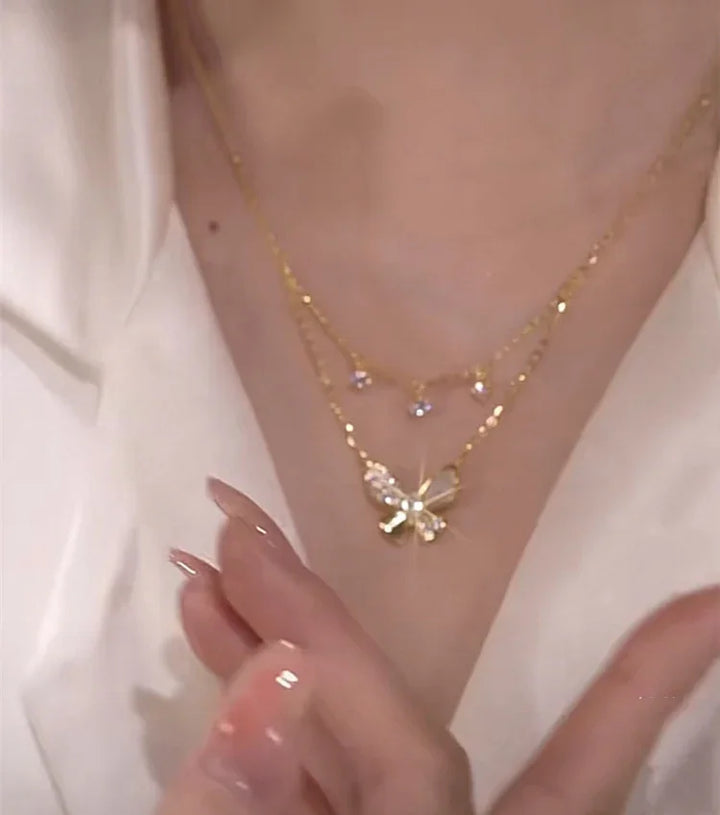 Close-up of a women's double-layered butterfly necklace, intricate zirconia details and glowing mother-of-pearl.