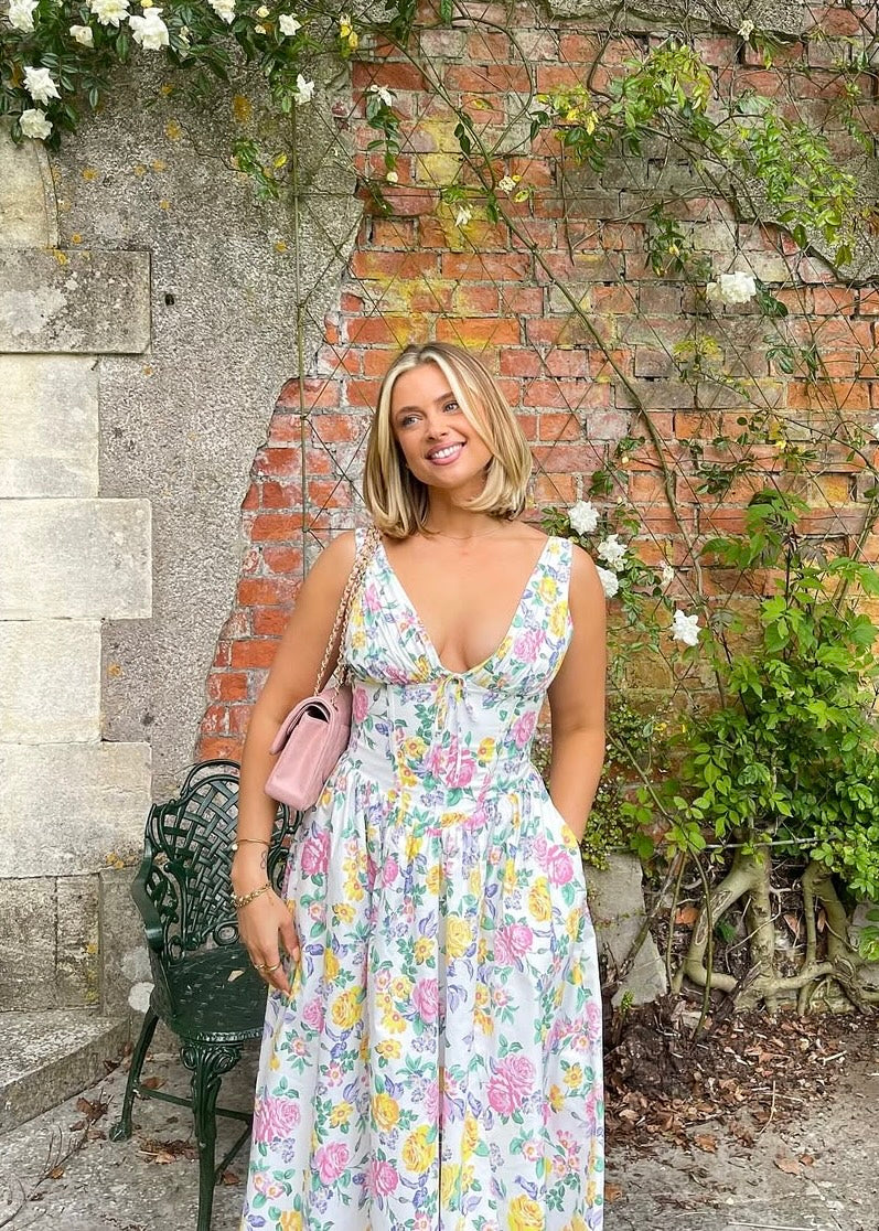 Close-up of the vibrant floral pattern and corset detail on a women's v-neck wedding guest midi dress.