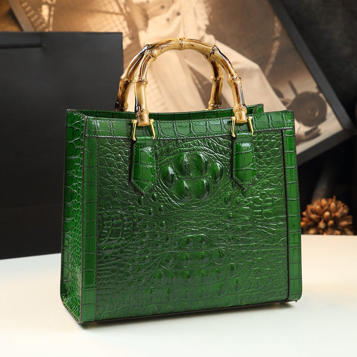 Fashionable women's genuine leather handbag with a distinctive croc pattern and bamboo handle.