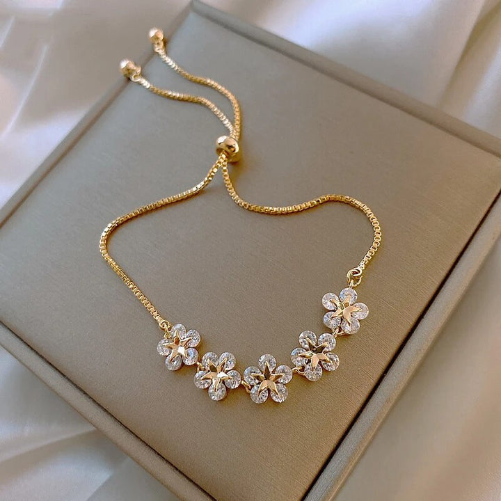 Elegant women's gold bracelet with sparkling crystal flowers. Perfect luxury floral jewelry for a romantic touch.