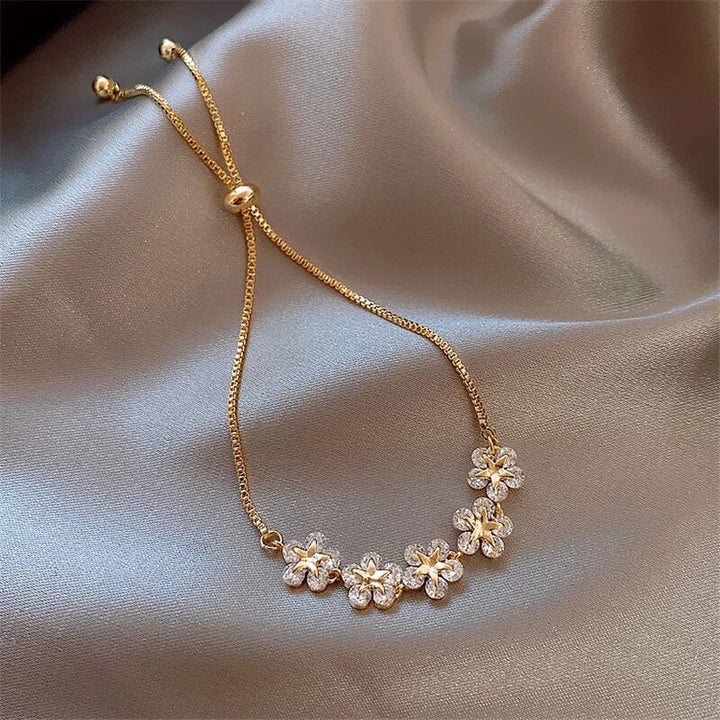 Women's gold crystal flower bracelet, a luxurious floral jewelry piece. Shimmering crystals on an elegant gold band.