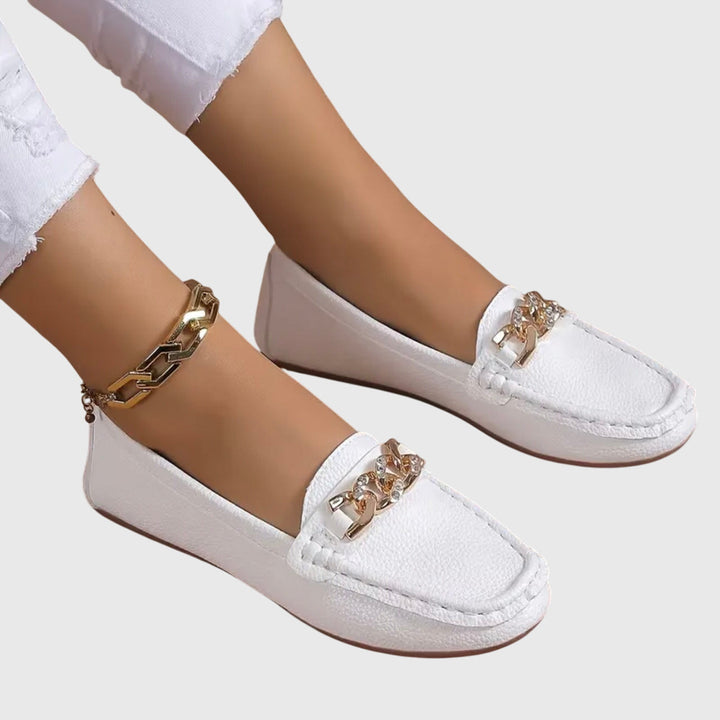 Fashionable women's slip-on wedge loafers, combining comfort, glam, and a gold chain.