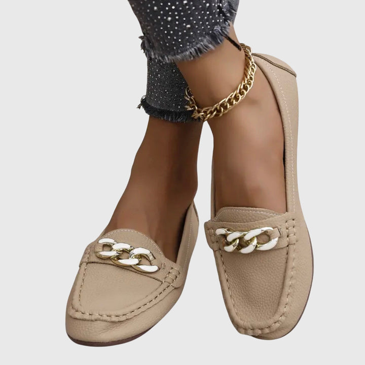 Women's gold-chain wedge loafers worn on foot, highlighting their elegant style and comfort.