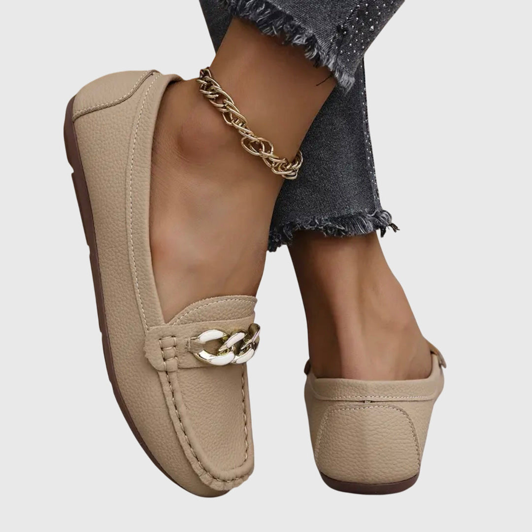 Close-up of the glamorous gold chain and crystal detail on women's wedge loafers.