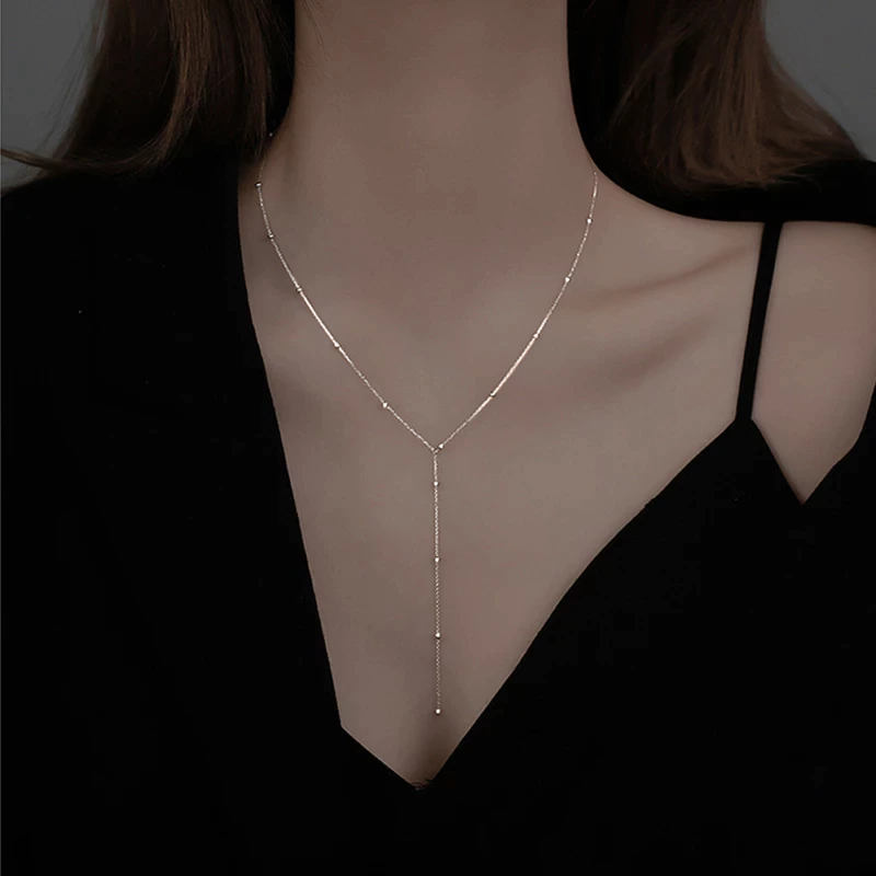 Elegant women's gold collarbone necklace with chic black tassels, perfect for sophisticated fashion. Adjustable.