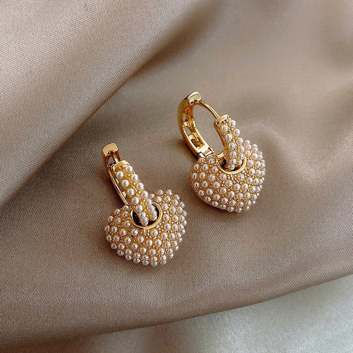 Elegant women's gold drop earrings with lustrous white pearls. Perfect fashion jewelry accessory.