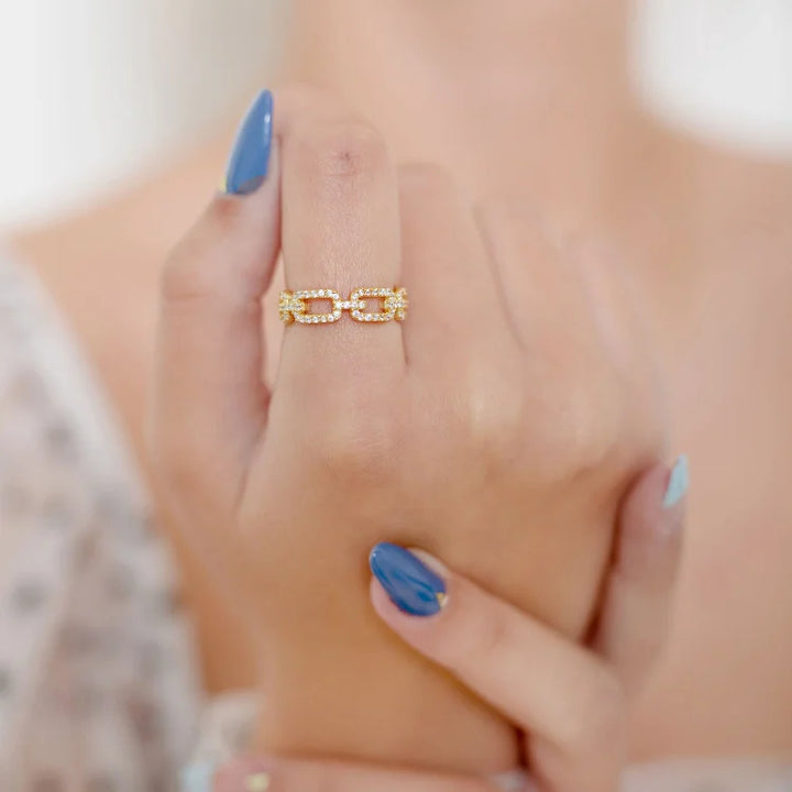 Close-up of a women's gold link ring adorned with shimmering zirconia stones. Elegant and high-quality fashion ring.